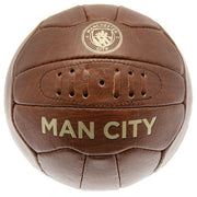 Brun læderfodbold med "MANCHESTER CITY" logo, synlige syninger og lufthuller.