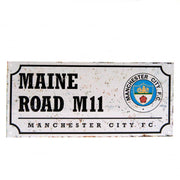 Metalskilt med "MAINE ROAD M11", Manchester City FC logo, slidt retro-look.