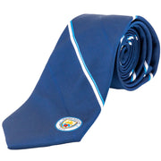 Blå slips med hvide og lyseblå striber, Manchester City-logo i hjørnet.