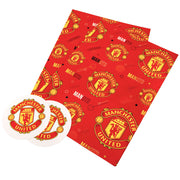 To ark rødt gavepapir og to runde mærker med Manchester United-logoer.