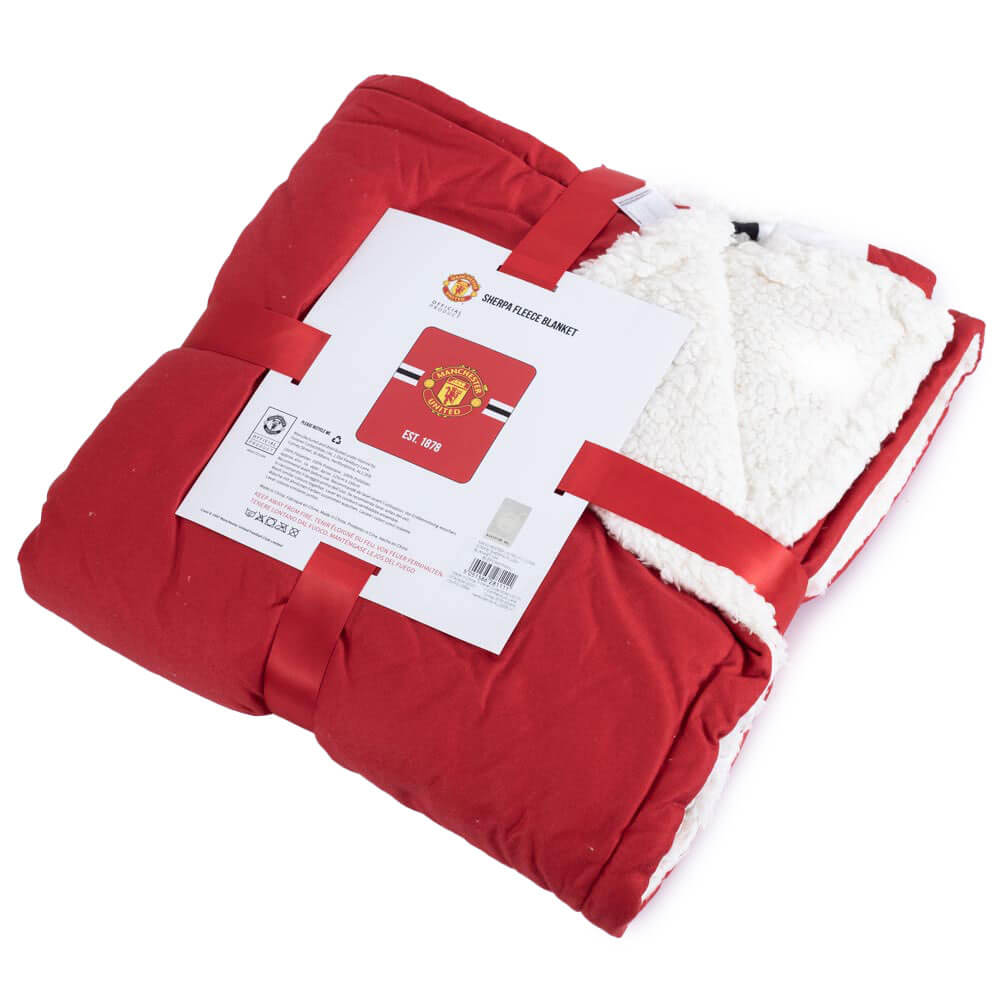 Rød Manchester United Sherpa fleece tæppe, pakket med logo og hvid inderside.