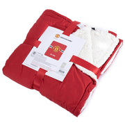 Rød Manchester United Sherpa fleece tæppe, pakket med logo og hvid inderside.