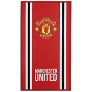 Rødt håndklæde med Manchester United-logo, sorte og hvide striber, "MANCHESTER UNITED" i hvidt nederst.