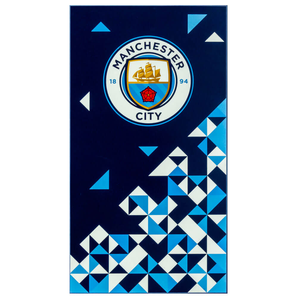 Manchester City håndklæde med logo og geometriske mønstre på mørk baggrund.
