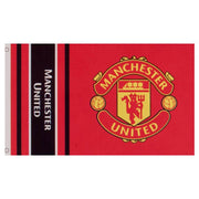 Manchester United-flag med klubemblem på rød baggrund, sorte/røde striber og hvid tekst til venstre.