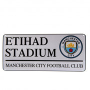 Metal skilt med "ETIHAD STADIUM", "MANCHESTER CITY FOOTBALL CLUB" og klubbens logo.